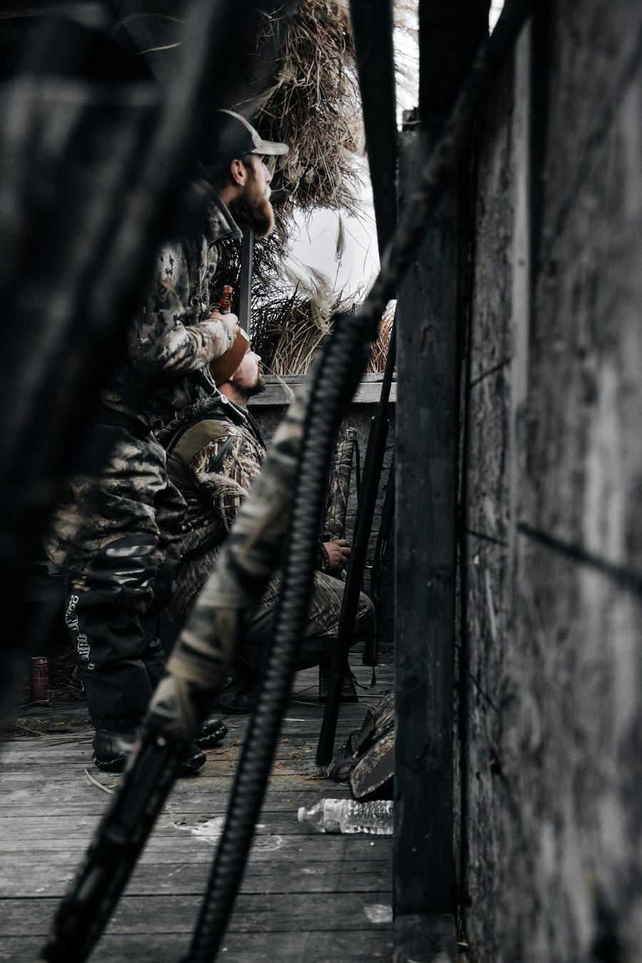 Duck hunters in camouflage waiting in a grass blind